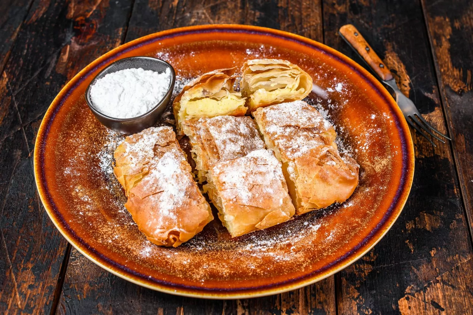 Sliced Greek Bougatsa pie with phyllo dough and semolina custard cream.